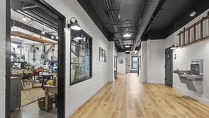 Un vaste couloir doté d’un plancher en bois, de grandes fenêtres et d’un éclairage moderne.