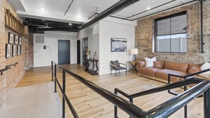 Un intérieur spacieux avec un plancher en bois, un canapé en cuir, une petite table avec une lampe et une grande fenêtre donnant sur un beau paysage.