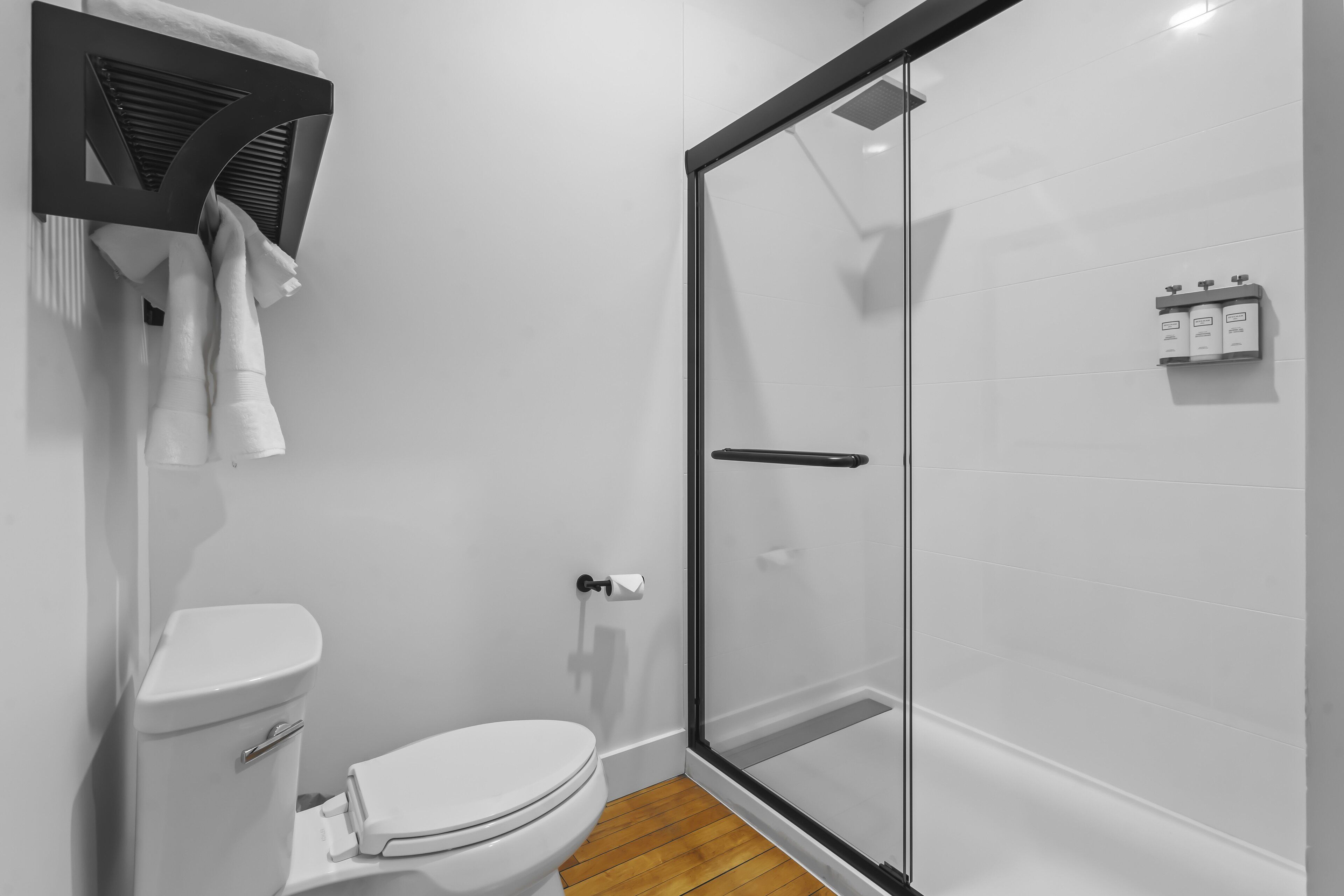 Une salle de bain moderne équipée de toilettes, d’une douche à parois de verre et d’un porte-serviettes.