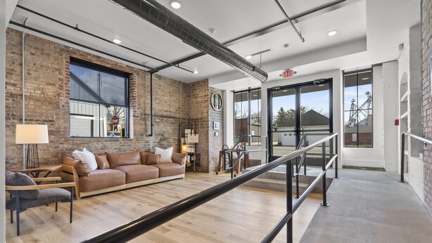 Un intérieur moderne avec un canapé en cuir, un plancher en bois et un mur en briques.