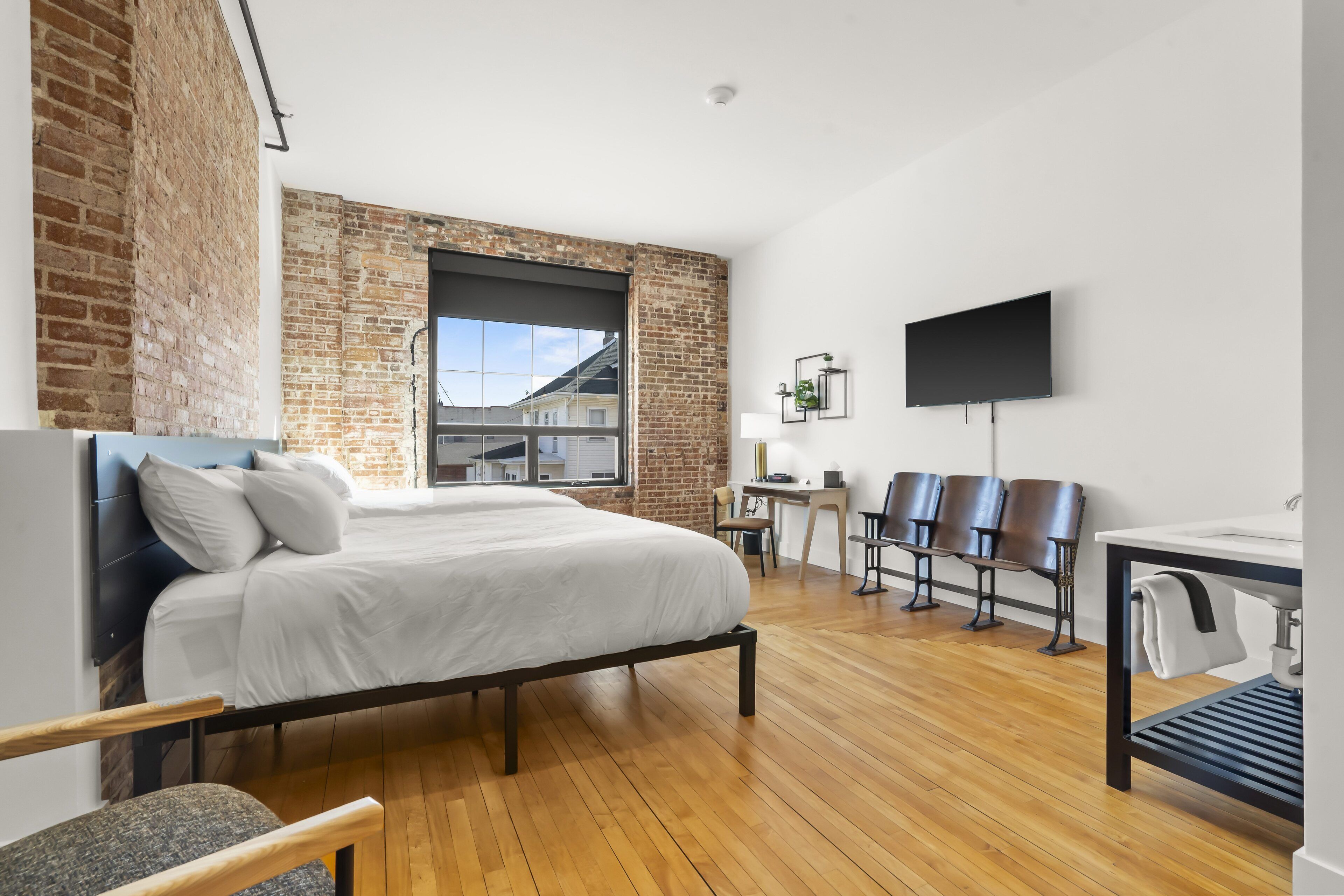 Une chambre d’hôtel moderne, dotée d’un grand lit, d’un bureau et d’une télévision.