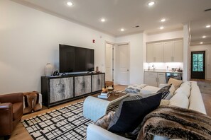 A modern living room with a large flat-screen TV, a dark wood cabinet, a light-colored sofa, and a patterned rug. - The SLOHouse, Walk to Sq+Campus, VelvetDitchVillas (Oxford)