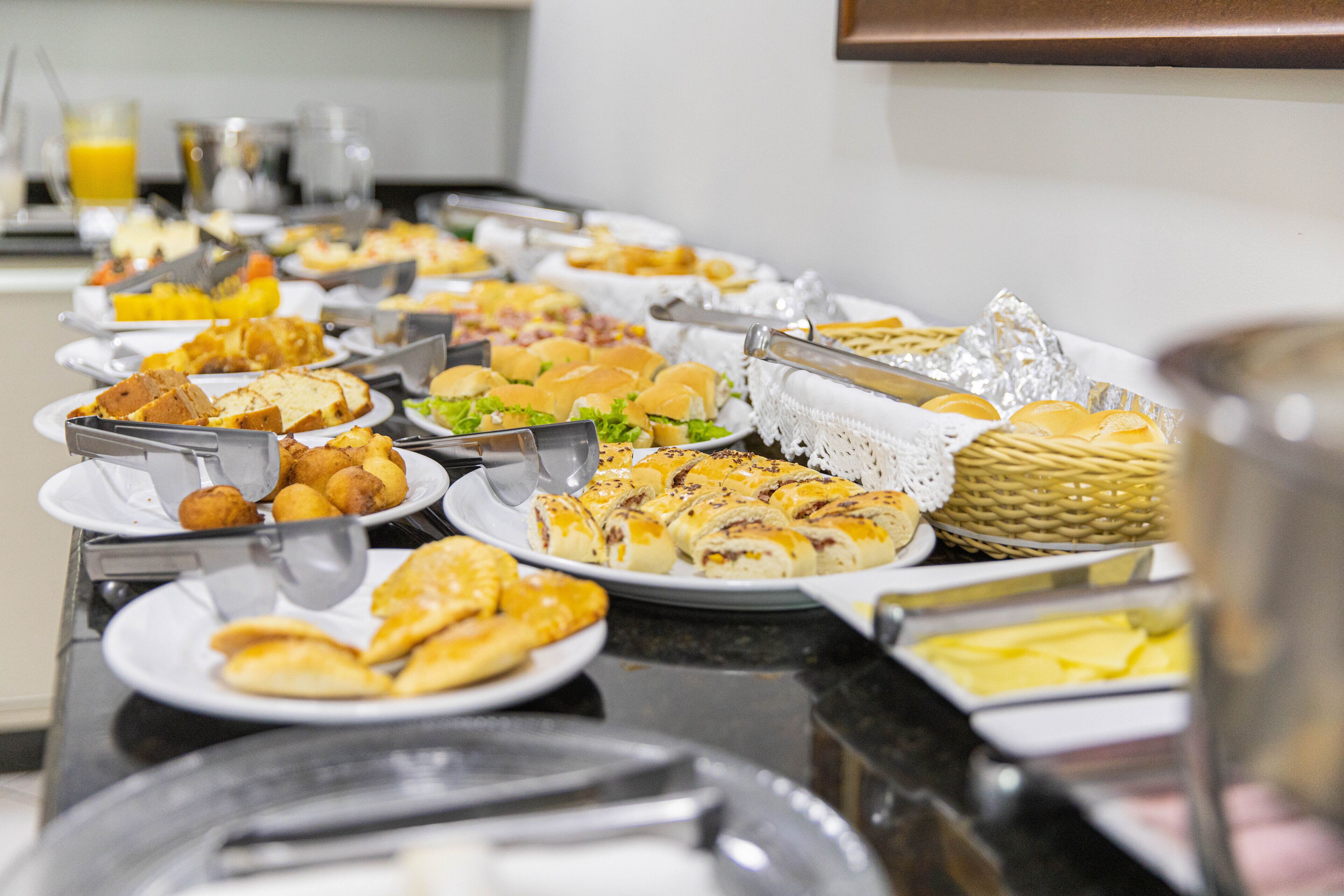 Een buffet met diverse etenswaren, zoals belegde broodjes, gebak en fruit.