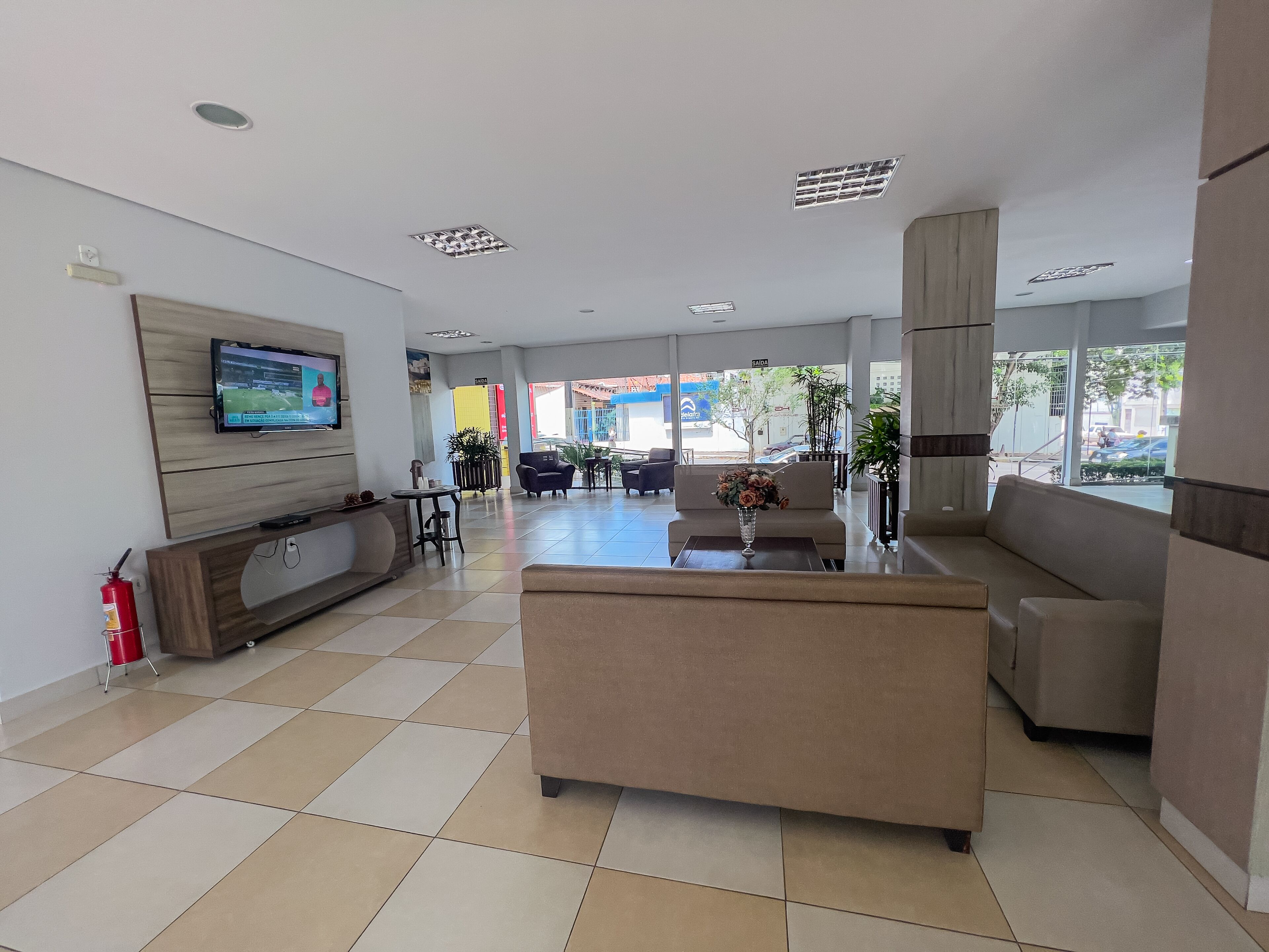 A modern lobby with a TV, seating area, and a fire extinguisher.