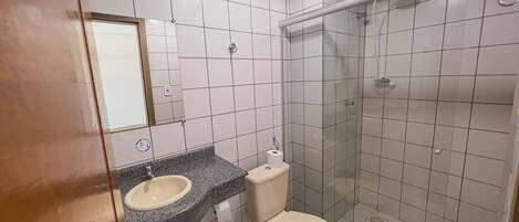 Un baño con lavabo, inodoro y cabina de ducha con paredes de vidrio.