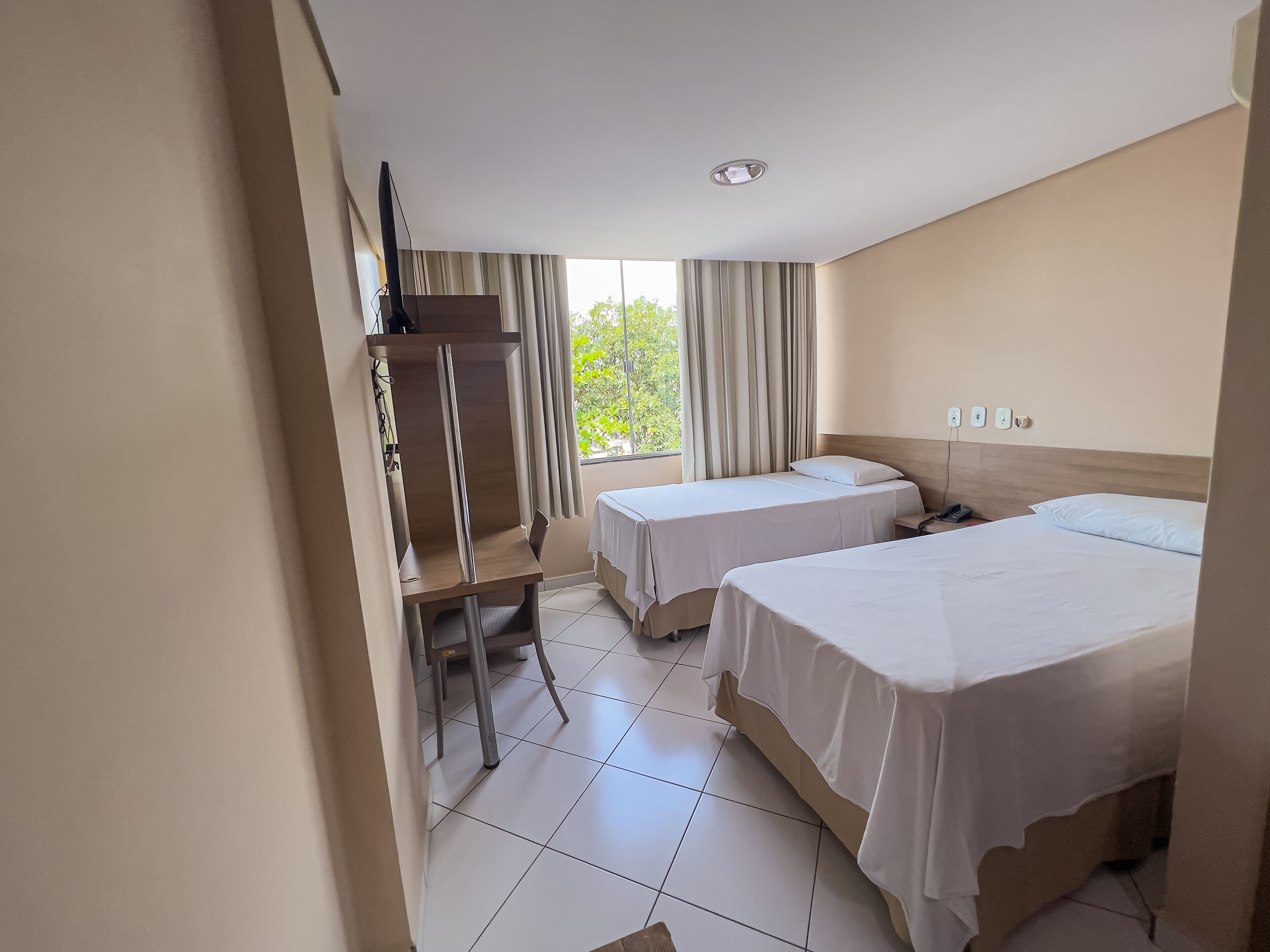 A hotel room with two beds, a desk, and a chair.