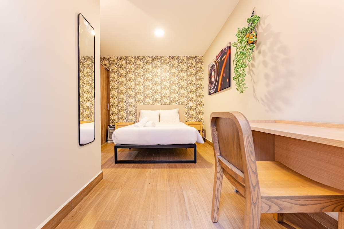 Un dormitorio moderno con cama, mesitas de noche, escritorio y silla.
