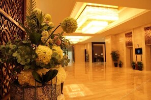 A spacious hotel lobby with a large floral arrangement, a high ceiling with a central light fixture, and a polished marble floor. - Lvshou Hotel Shanghai (Shanghai)