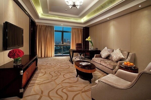 Une chambre d’hôtel moderne dotée d’une grande fenêtre, d’un canapé, d’une table basse et d’un téléviseur.