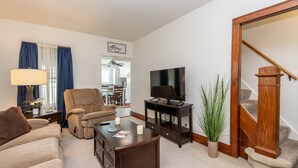 A living room with a sofa, armchair, coffee table, TV, and a staircase. - 4BD House, Your Central Suburban Oasis, City Lights, Quiet Nights (Wauwatosa)