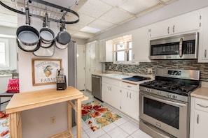 A modern kitchen with stainless steel appliances, white cabinetry, and a wooden table.