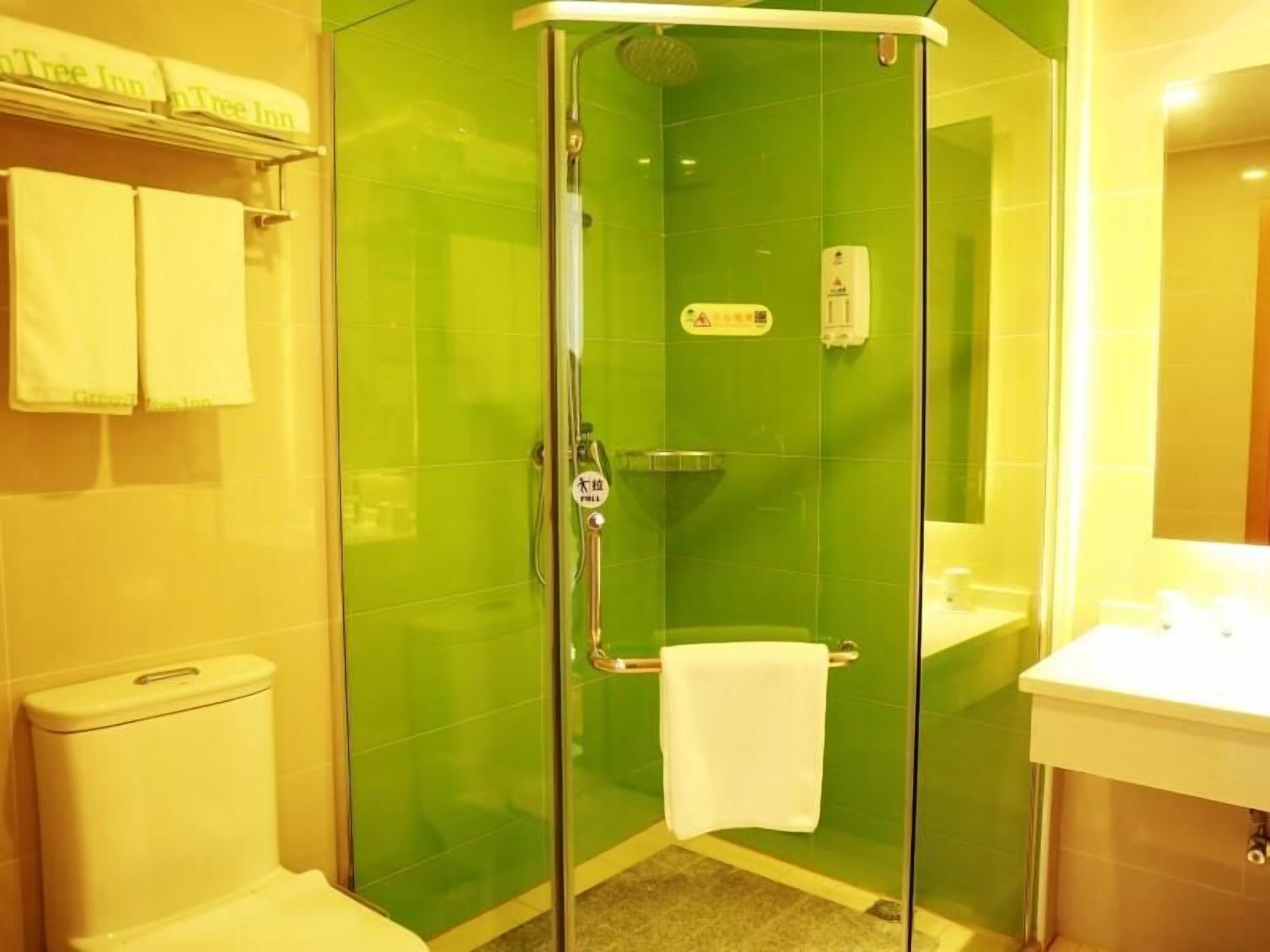 A bathroom with a glass-enclosed shower, a toilet, and a sink.