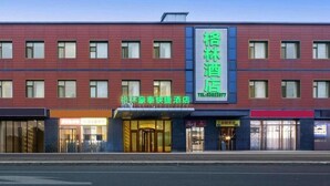 Un hôtel reconnaissable à son grand panneau vert, à ses nombreuses fenêtres et à sa façade moderne.