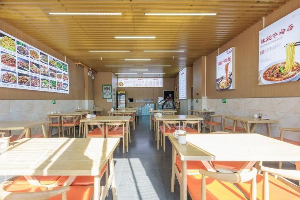 Un interior de restaurante con mesas y sillas de madera, pizarras con el menú en las paredes y una barra al fondo.