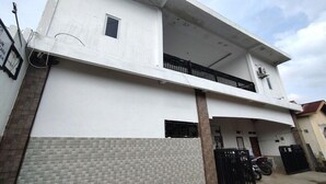 Un bâtiment à deux étages doté d’un balcon à l’étage supérieur, d’une entrée fermée par un portail et d’une partie inférieure recouverte de carreaux.