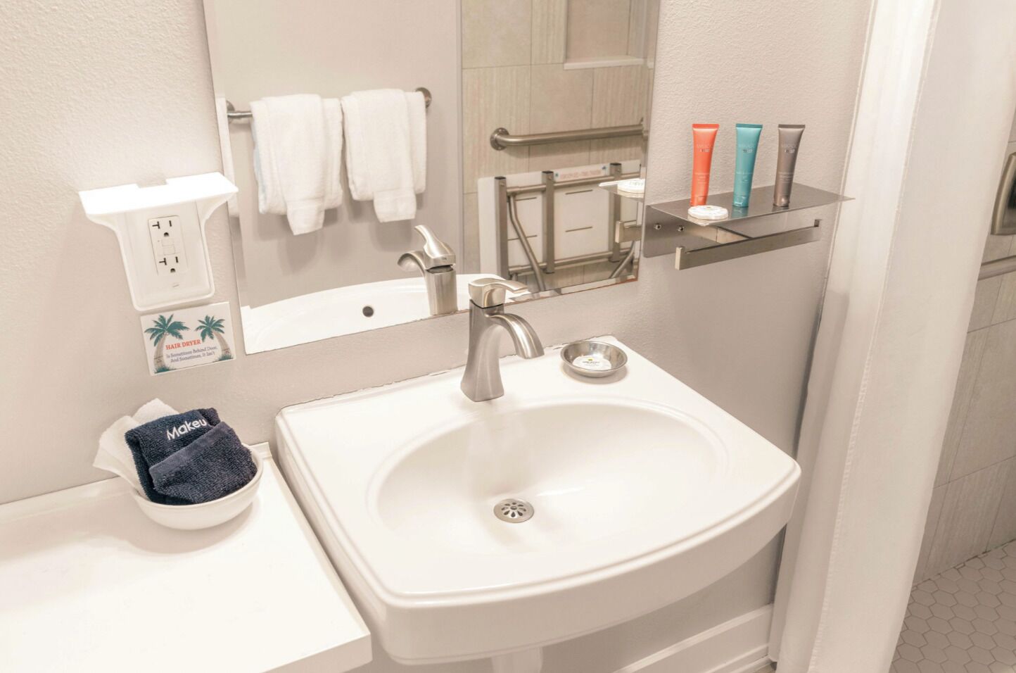 A bathroom with a white sink, a hair dryer, and a mirror.