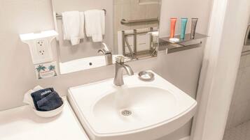 A bathroom with a white sink, a hair dryer, and a mirror.