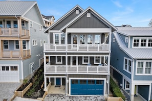 A multi-story residential building with a blue garage, a balcony on the second floor, and a small front porch. - *New* Seabrook's Solitude: Private Hot Tub & Dog Friendly (Pacific Beach)