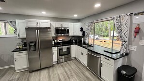 Una cucina moderna con elettrodomestici in acciaio inossidabile, mobili bianchi e un piano di lavoro nero.