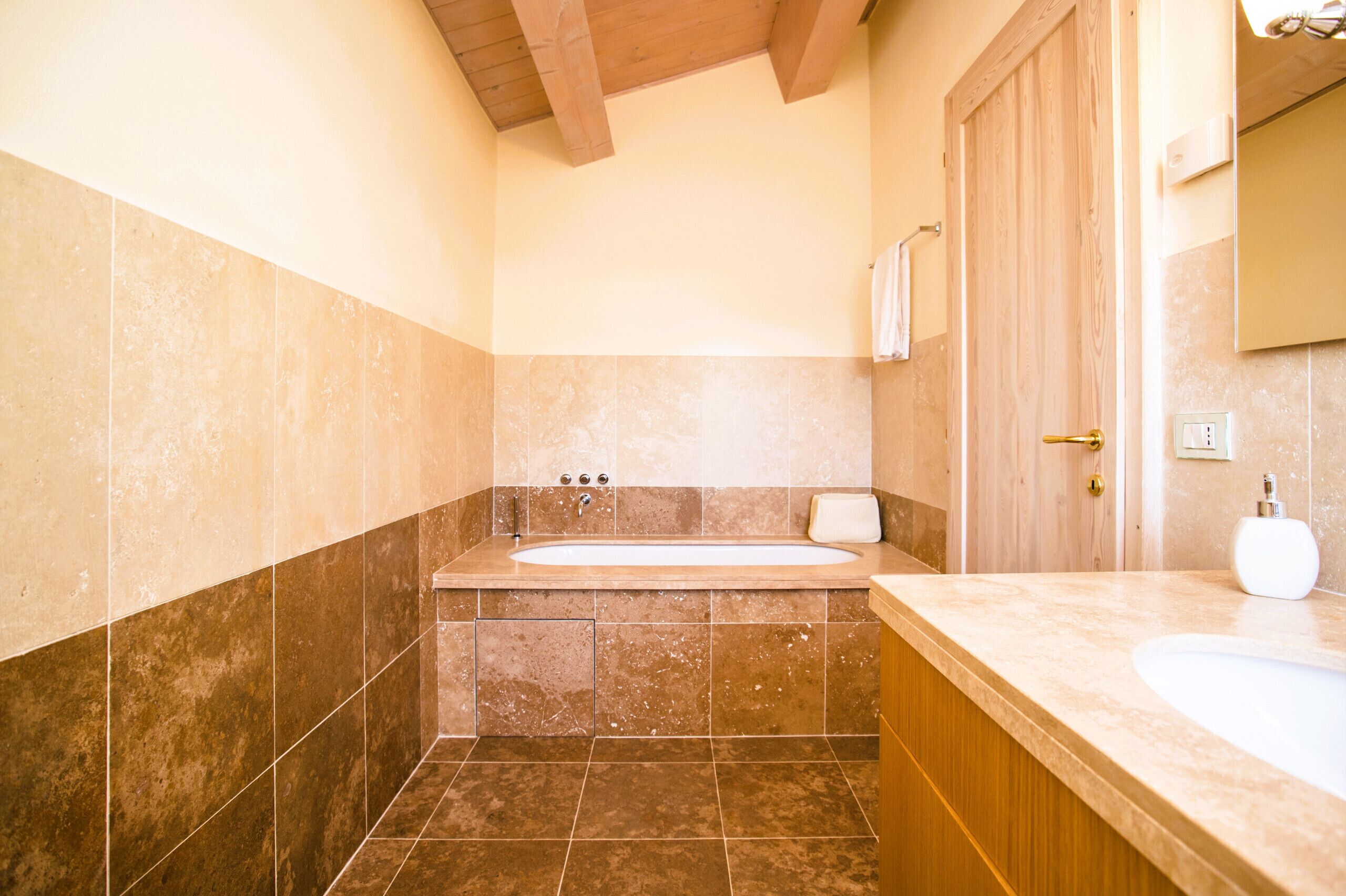Un baño con bañera, lavamanos y puerta de madera.