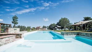 Ein Schwimmbecken mit Steinstufen und einer Pergola.