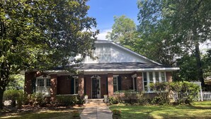 A two-story brick house with a front porch, a small garden, and a white picket fence. - Cozy Carriage House 2 Blocks from Oxford Square (Oxford)