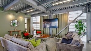 Un salon moderne doté d’un grand téléviseur, de sièges confortables et d’un escalier.