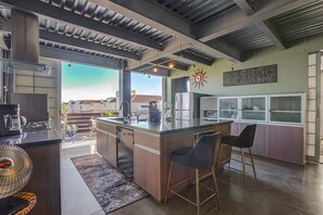 Eine moderne Küche mit einer großen Kochinsel, Barhocker und Blick auf die Nachbarschaft.