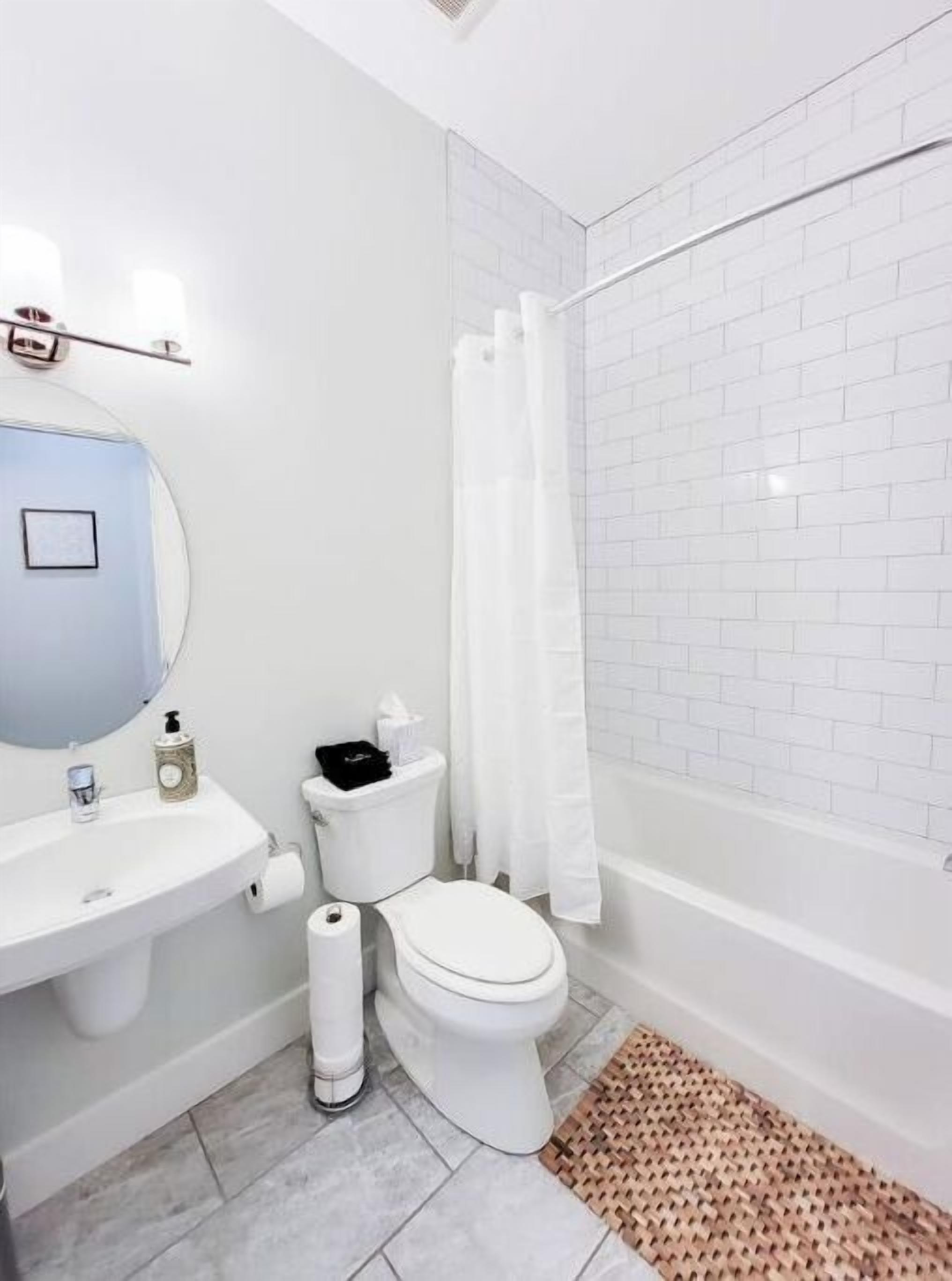 A bathroom with a white sink, toilet, and shower area.