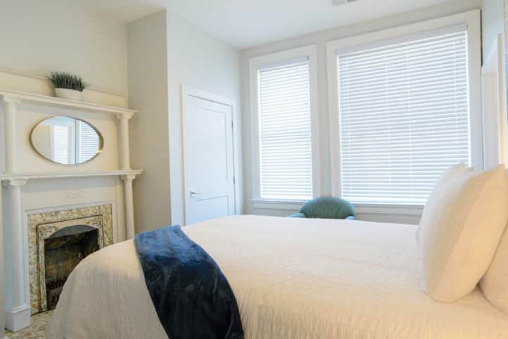 Une chambre à coucher avec un grand lit, une cheminée et une fenêtre équipée de stores.