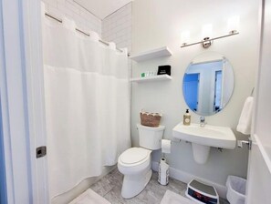 Ein Badezimmer mit Toilette, Waschbecken, Spiegel und Duschvorhang.