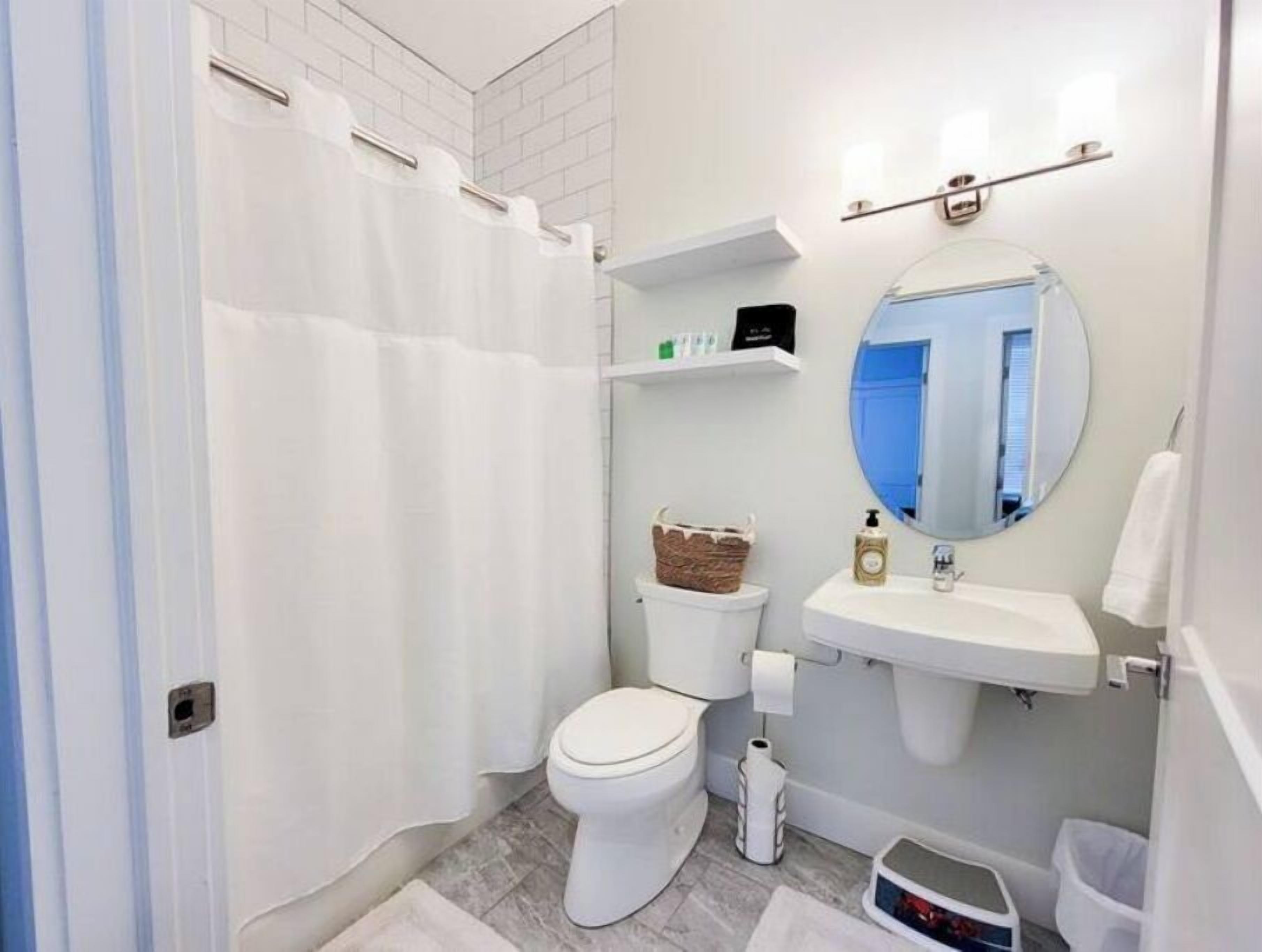 A modern bathroom with a white toilet, a sink with a mirror, and a shower curtain.
