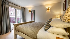 Un dormitorio con cama, cortinas, ventana e iluminación en la pared.
