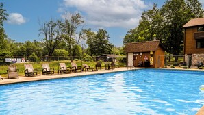 A swimming pool with lounge chairs and a wooden building in the background. - Spacious 4BR Retreat • Private Beach • Heated Outdoor Pool is OPEN • Golf Cart (Coloma)