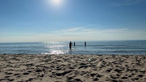 A beach with footprints leading to the water, a clear sky, and the sun shining. - Spacious 4BR Retreat • Private Beach • Heated Outdoor Pool is OPEN • Golf Cart (Coloma)