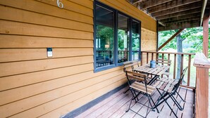 A wooden exterior with a number '30-6' on the wall, a covered porch with a table and benches, and a view of greenery outside. - Spacious 4BR Retreat • Private Beach • Heated Outdoor Pool is OPEN • Golf Cart (Coloma)