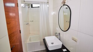 A bathroom with a bathtub, a sink, and a mirror.