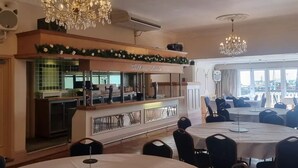 Ein Restaurant mit runden Tischen, Kronleuchtern und Meerblick.