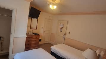 A hotel room with two beds, a dresser, a mirror, and a ceiling light fixture.