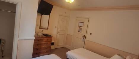 A hotel room with two beds, a dresser, a mirror, and a ceiling light fixture.