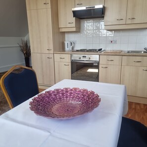 A compact kitchen with wooden cabinets, a built-in oven, and a white tiled backsplash. - The Royal Oak Hotel (Ramsgate)