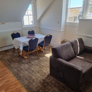 A dining area with a table and chairs, a patterned rug, and a sofa. - The Royal Oak Hotel (Ramsgate)