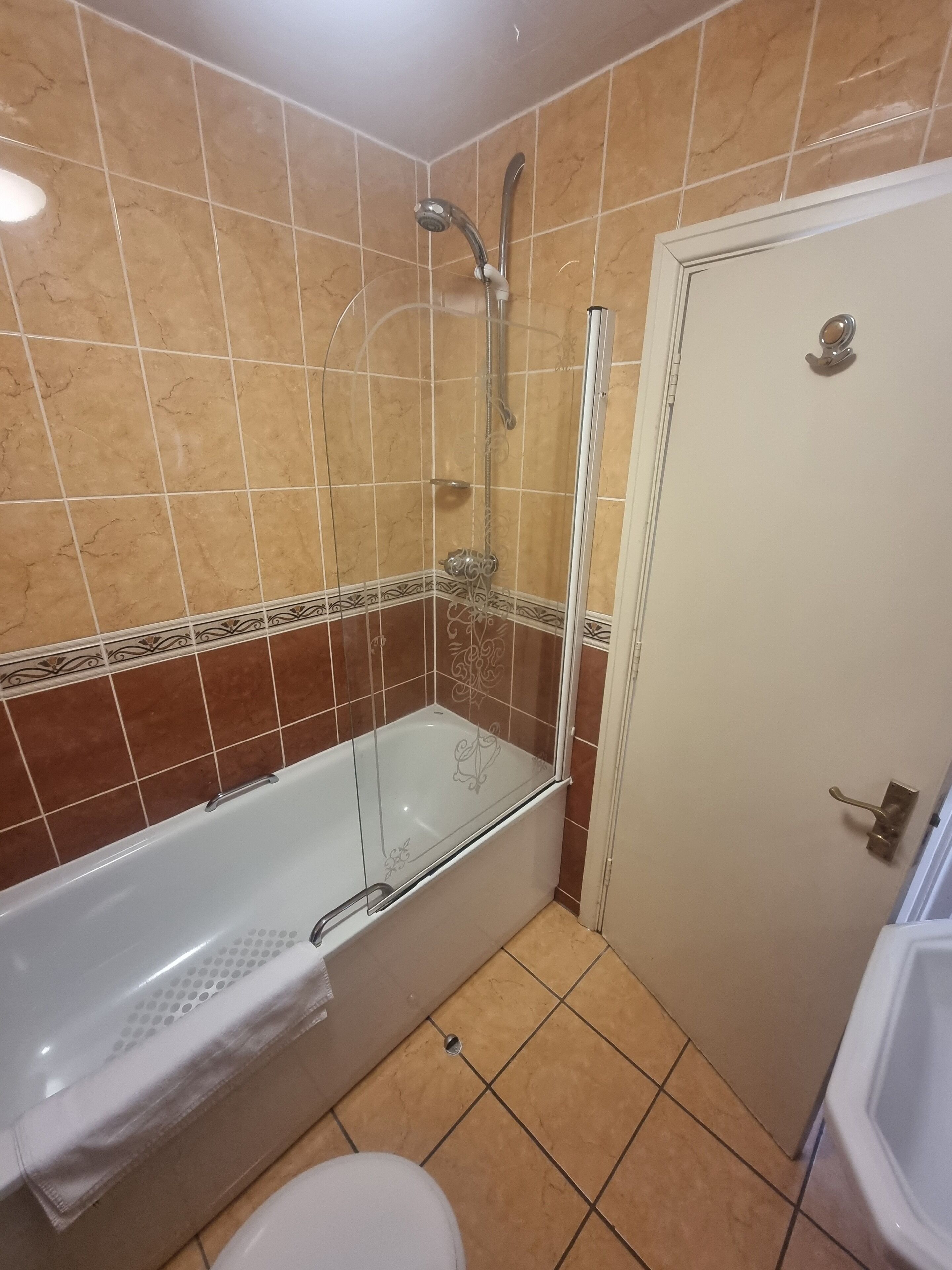 A bathroom with a glass-enclosed shower, a white bathtub, and a toilet.