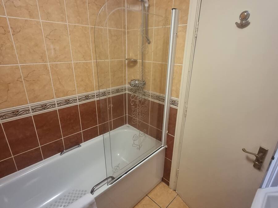 A bathroom with a glass-enclosed shower, a white bathtub, and a toilet.