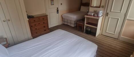 Una habitación de hotel con una cama grande, un escritorio con una silla, un televisor y un espejo.