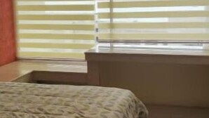 A bedroom with a bed, a window with blinds, and a small window sill.