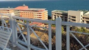 A balcony with a view of the sea and buildings in the background.