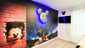 A room with a brick wall mural featuring Mickey Mouse and a night sky with the moon. - Coral Way Private Pool  (Kissimmee)