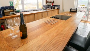 A modern kitchen with wooden cabinets, a built-in stove, and a large window. - The Bike Shed (High Peak)
