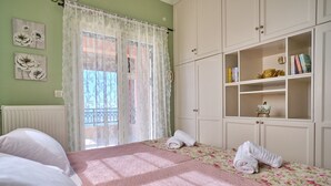 Une chambre à coucher avec un lit, une fenêtre avec un rideau, un radiateur et une armoire contenant des livres et une petite figurine.